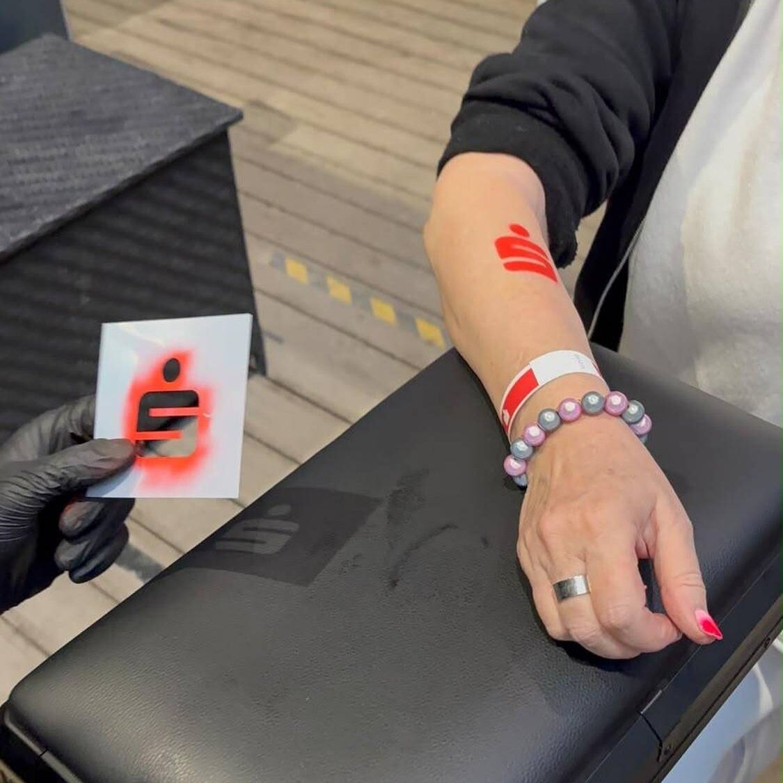 Airbrush Tattoo mit Sparkasse Logo am Handgelenk eines Gastes